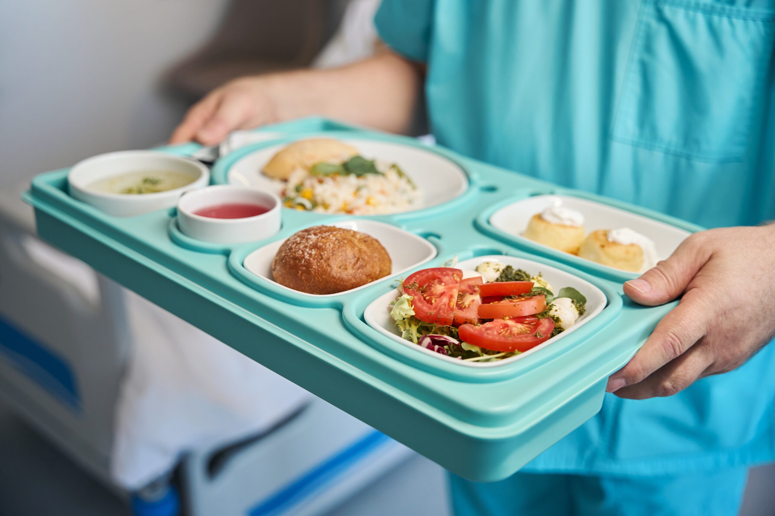 hospital worker carrying tray of diet manual approved food to a patient
