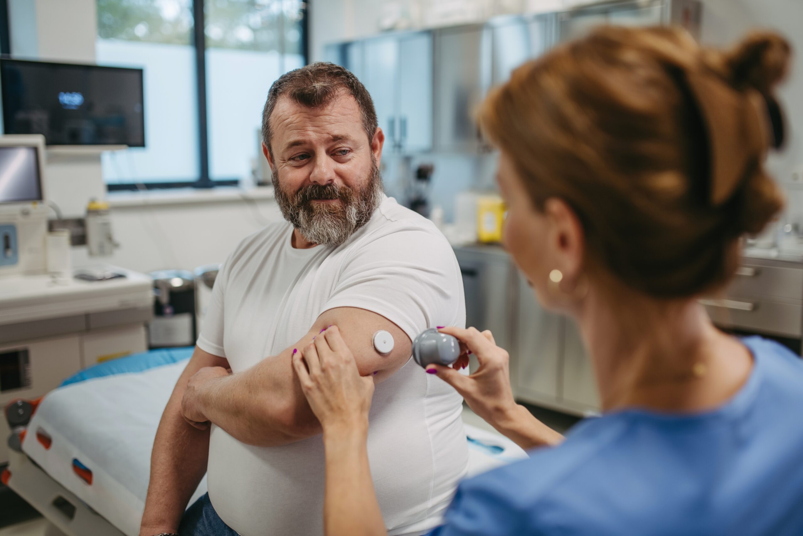male patient in white t-shirt receiving care from a female healthcare professional